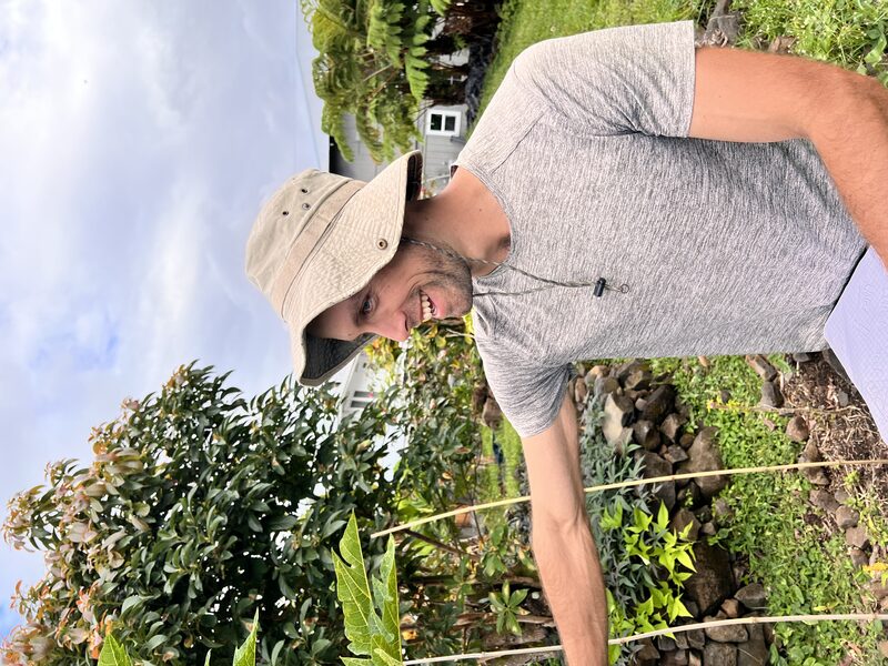 Erik smiling among the plants in his garden